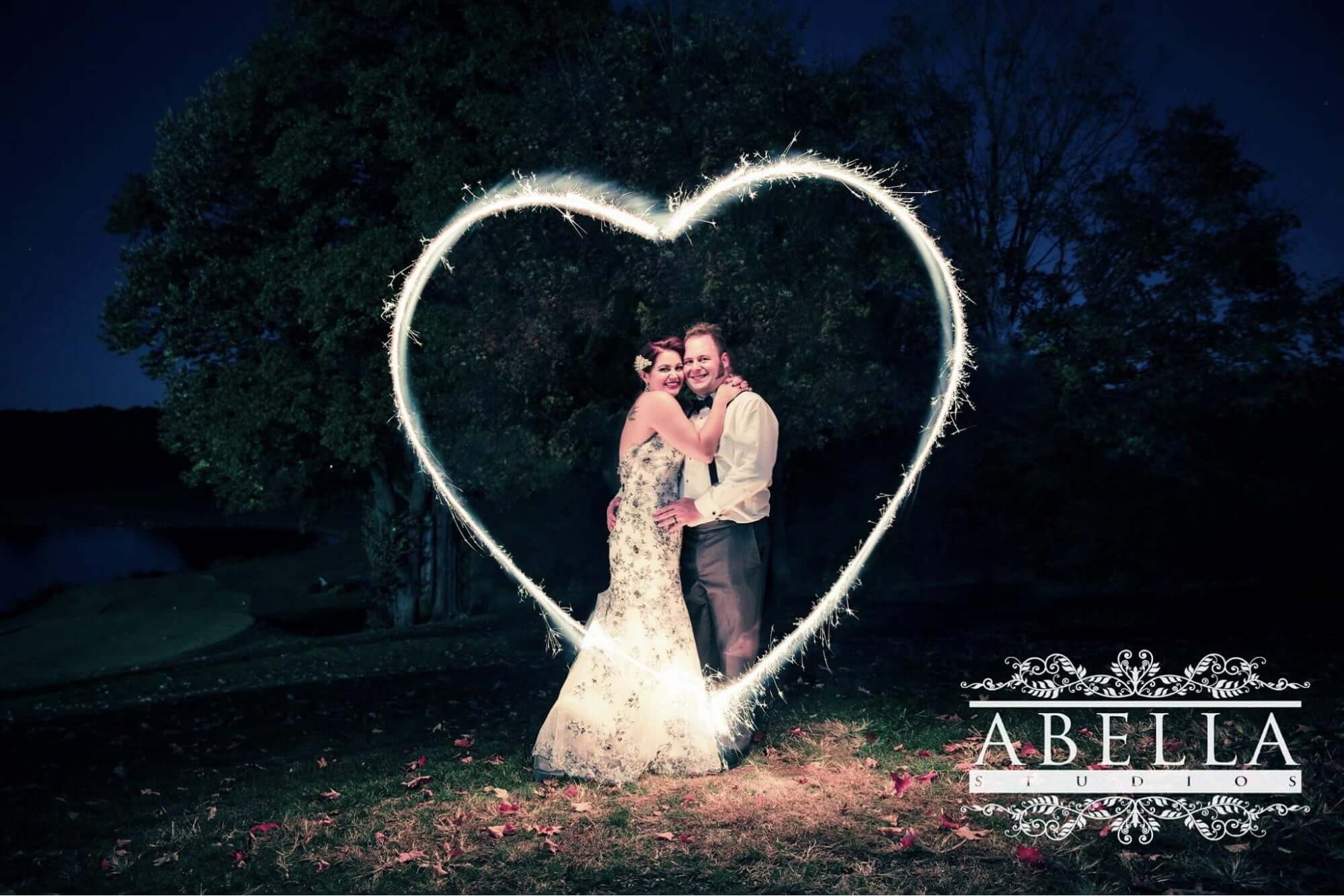 Bride and Groom standing outside behind a heart sparkler