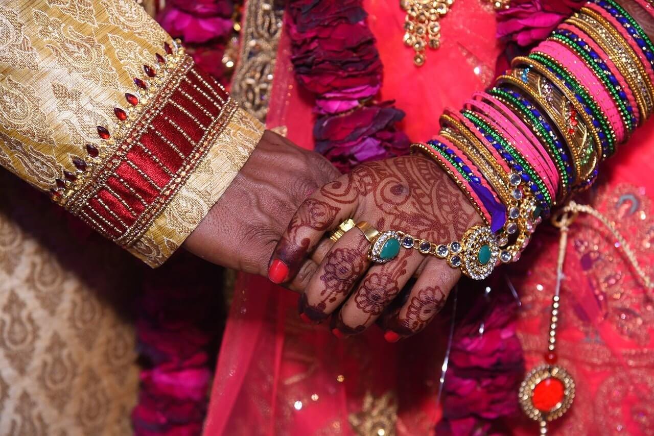 An Indian couple, happily bonded in matrimony, hold each other's hands during their outdoor wedding ceremony at a picturesque New Jersey venue.